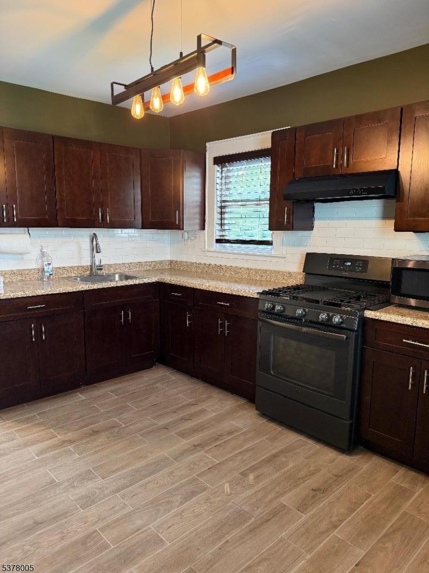 588 Chestnut Street, Unit 2 Orange, NJ 07050 - Photo 3 of 16 a kitchen with granite countertop a sink cabinets and stainless steel appliances