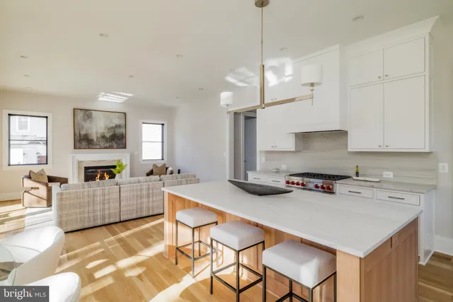 a kitchen with a stove a refrigerator a sink a dining table and chairs with wooden floor