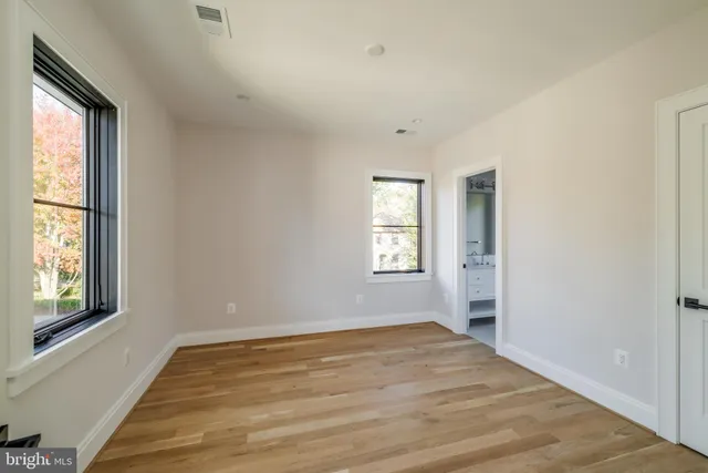 a view of empty room with wooden floor and fan