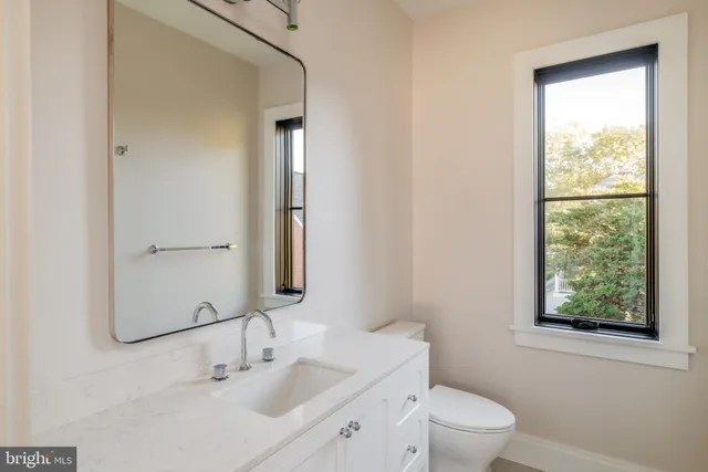 a bathroom with a toilet a sink a mirror and a window