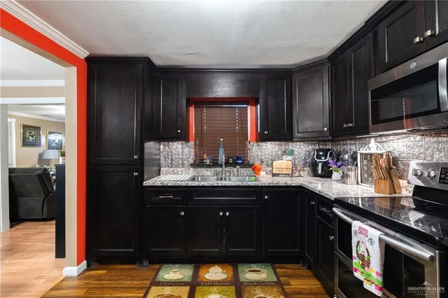 a kitchen with kitchen island granite countertop a sink cabinets and stainless steel appliances