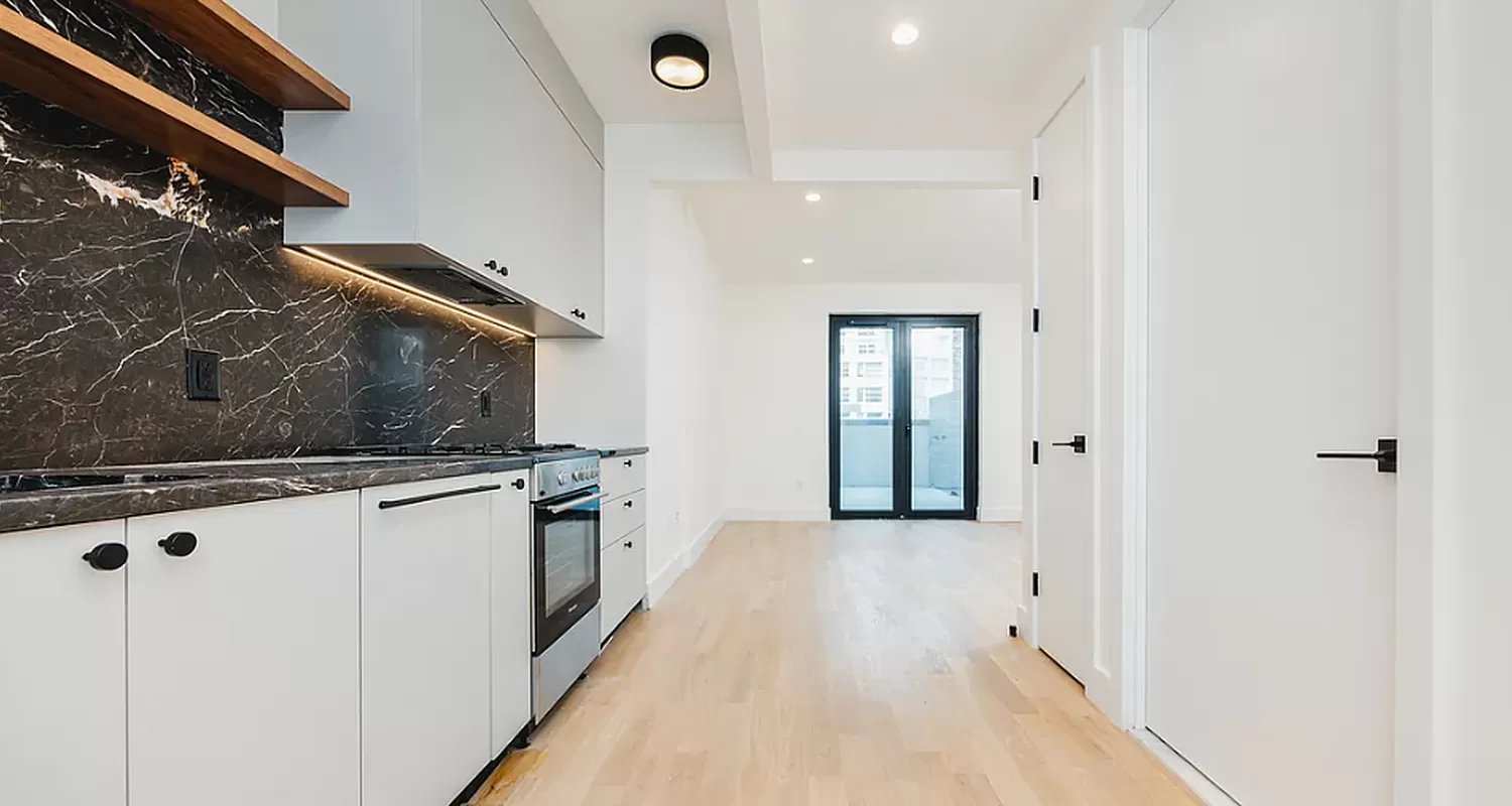 a hallway with white cabinets and stainless steel appliances