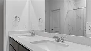 a bathroom with a granite countertop sink two mirror and shower