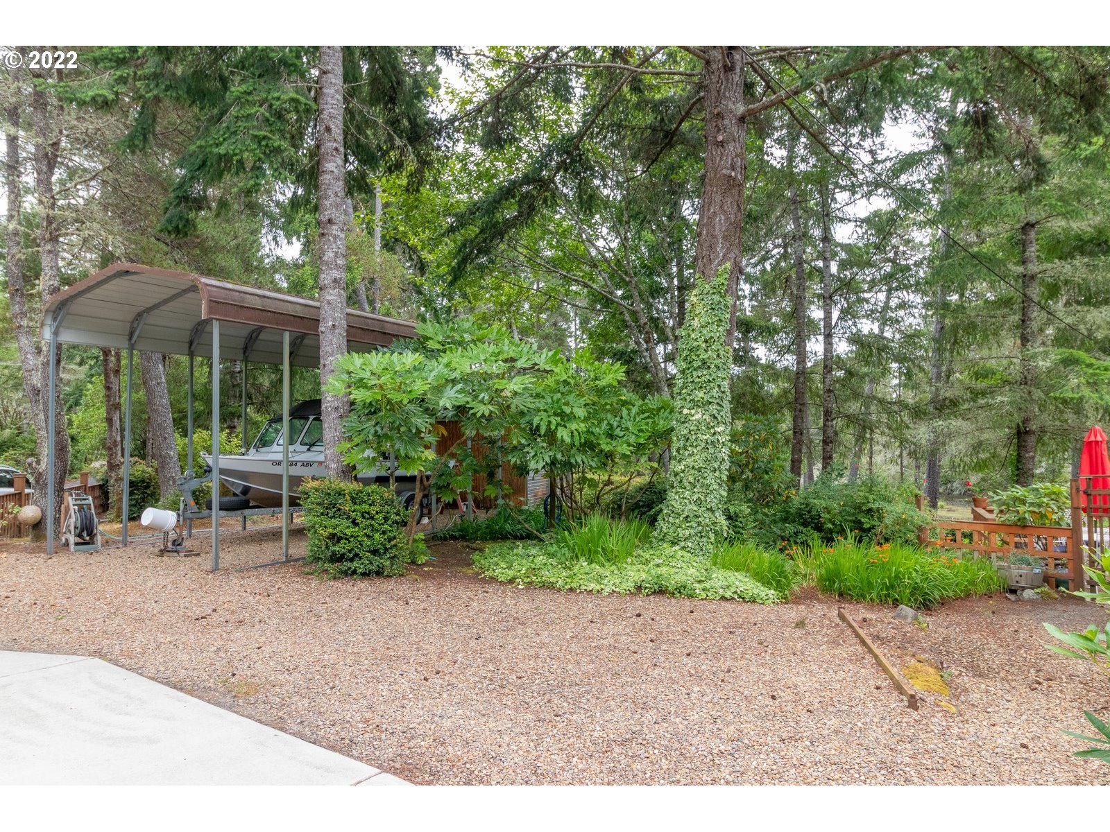 5732 Nicholson Road Florence, OR 97439 - Photo 26 of 31 a backyard of a house with table and chairs under an umbrella