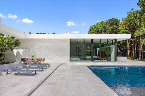 a view of swimming pool with a yard and palm trees
