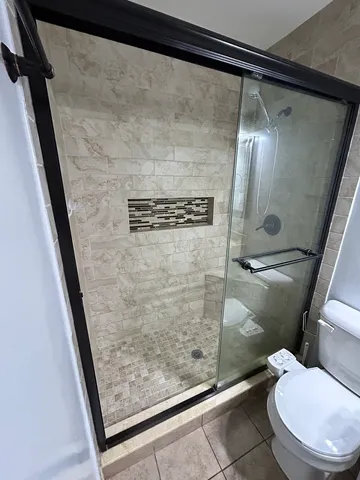 a bathroom with a granite countertop shower and a toilet