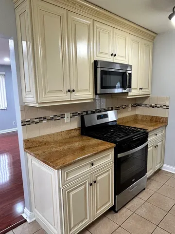 a kitchen with granite countertop a stove top oven microwave and cabinets