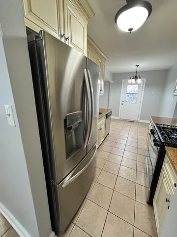 a view of a refrigerator in kitchen and an empty room