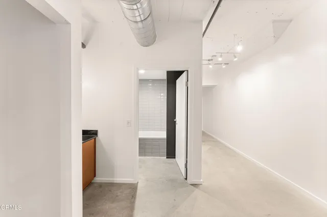 a view of a hallway with wooden floor and a bathroom