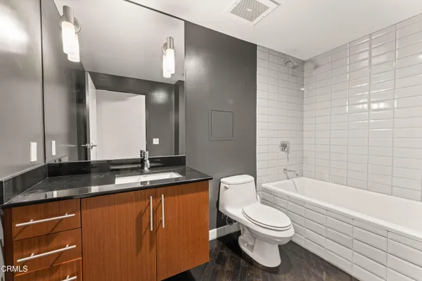 a bathroom with a granite countertop sink toilet a large mirror a bathtub and shower