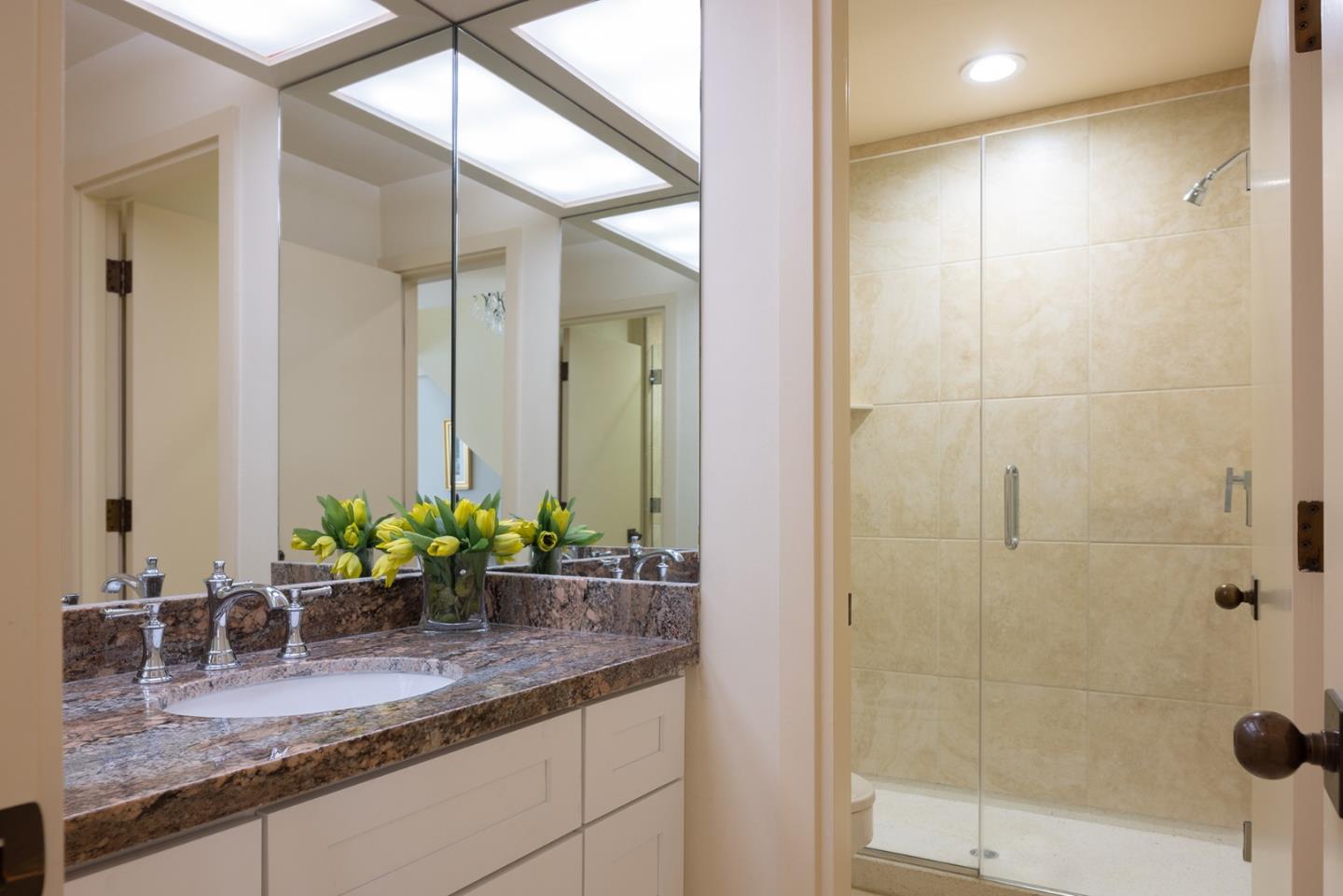 9621 Homestead Road Carmel, CA 93923 - Photo 19 of 30 a bathroom with a granite countertop sink a mirror and a shower