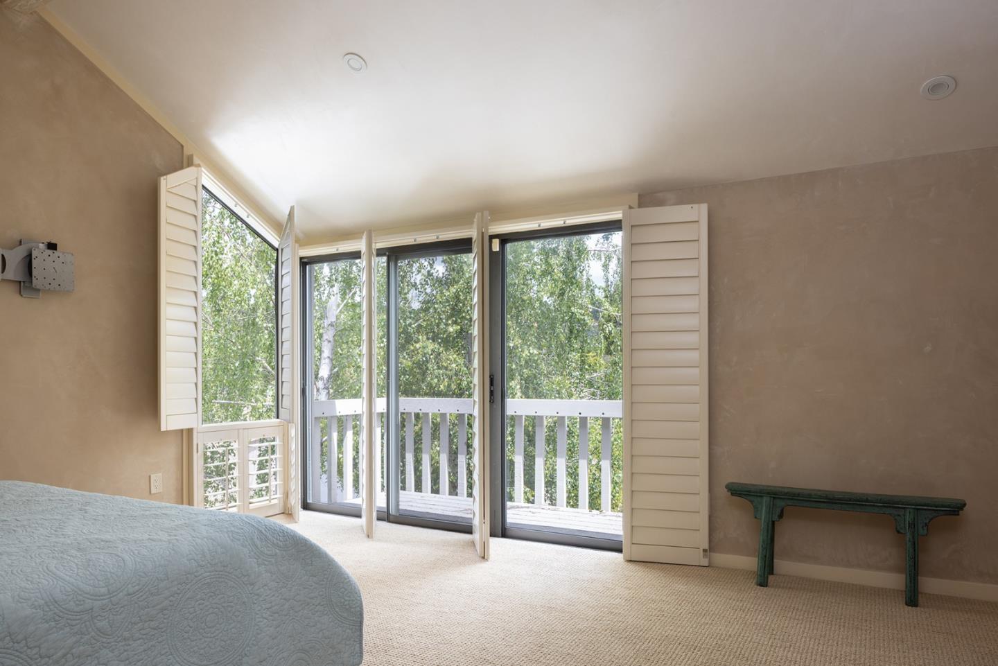 9621 Homestead Road Carmel, CA 93923 - Photo 20 of 30 a spacious bedroom with a balcony a bed and a chair