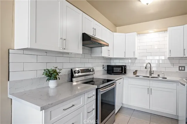 a kitchen with stainless steel appliances white cabinets and a stove top oven