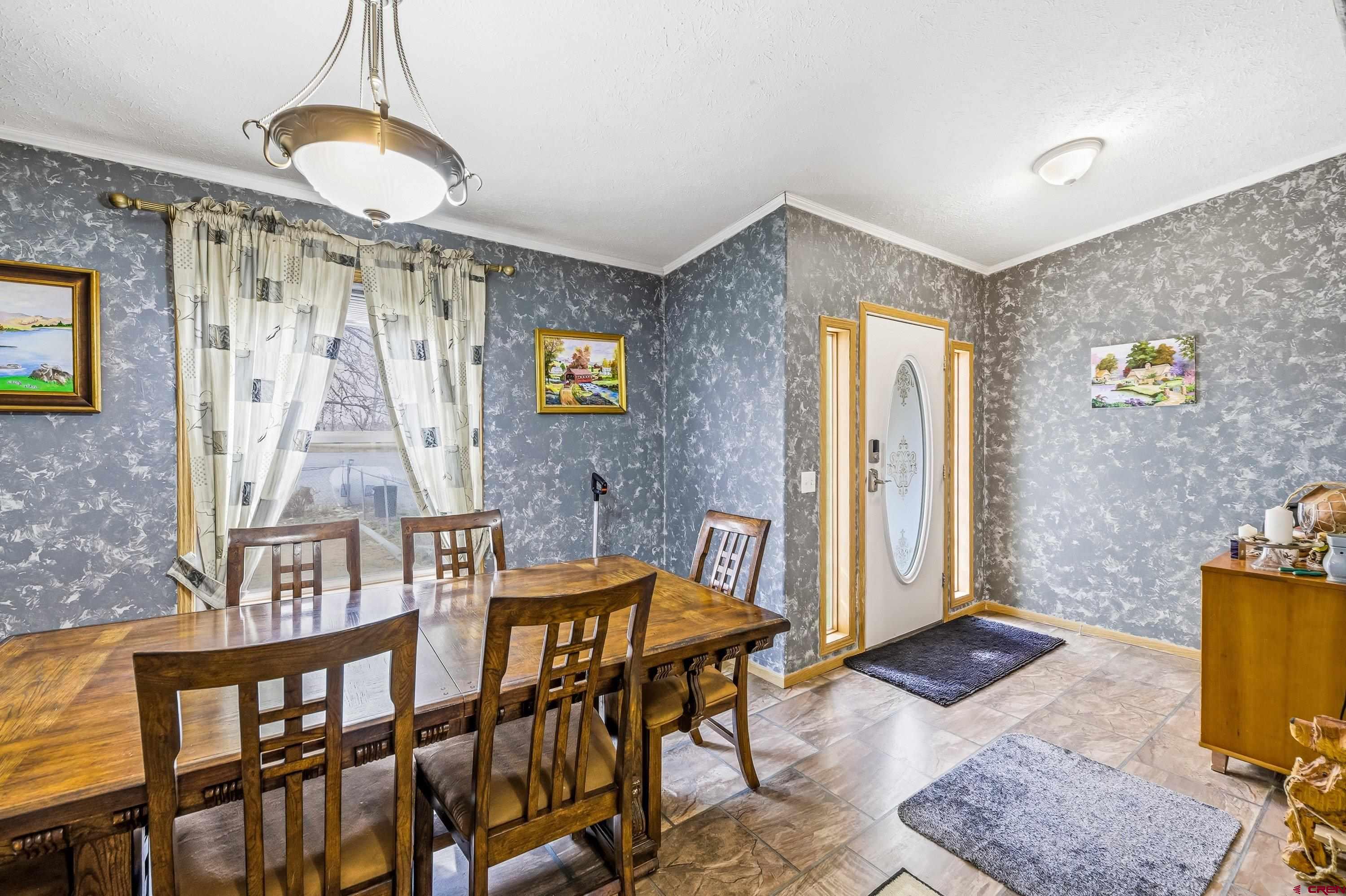 14473 Deer Run Road Delta, CO 81416 - Photo 3 of 26 a living room with a dining table and paintings on the wall