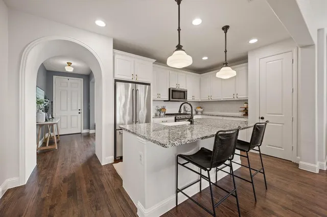 a kitchen with stainless steel appliances a dining table chairs refrigerator and microwave