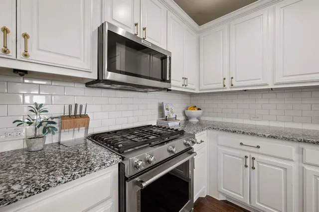 a kitchen with granite countertop white cabinets and stainless steel appliances