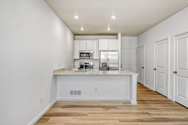a view of kitchen with stainless steel appliances granite countertop refrigerator sink and cabinets