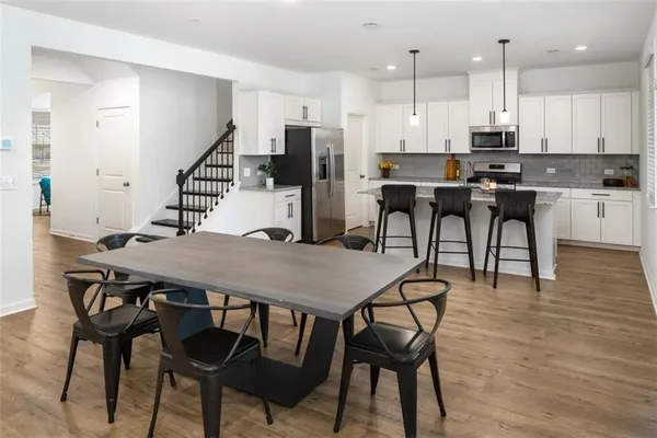 a kitchen with stainless steel appliances kitchen island granite countertop a table chairs stove and white cabinets
