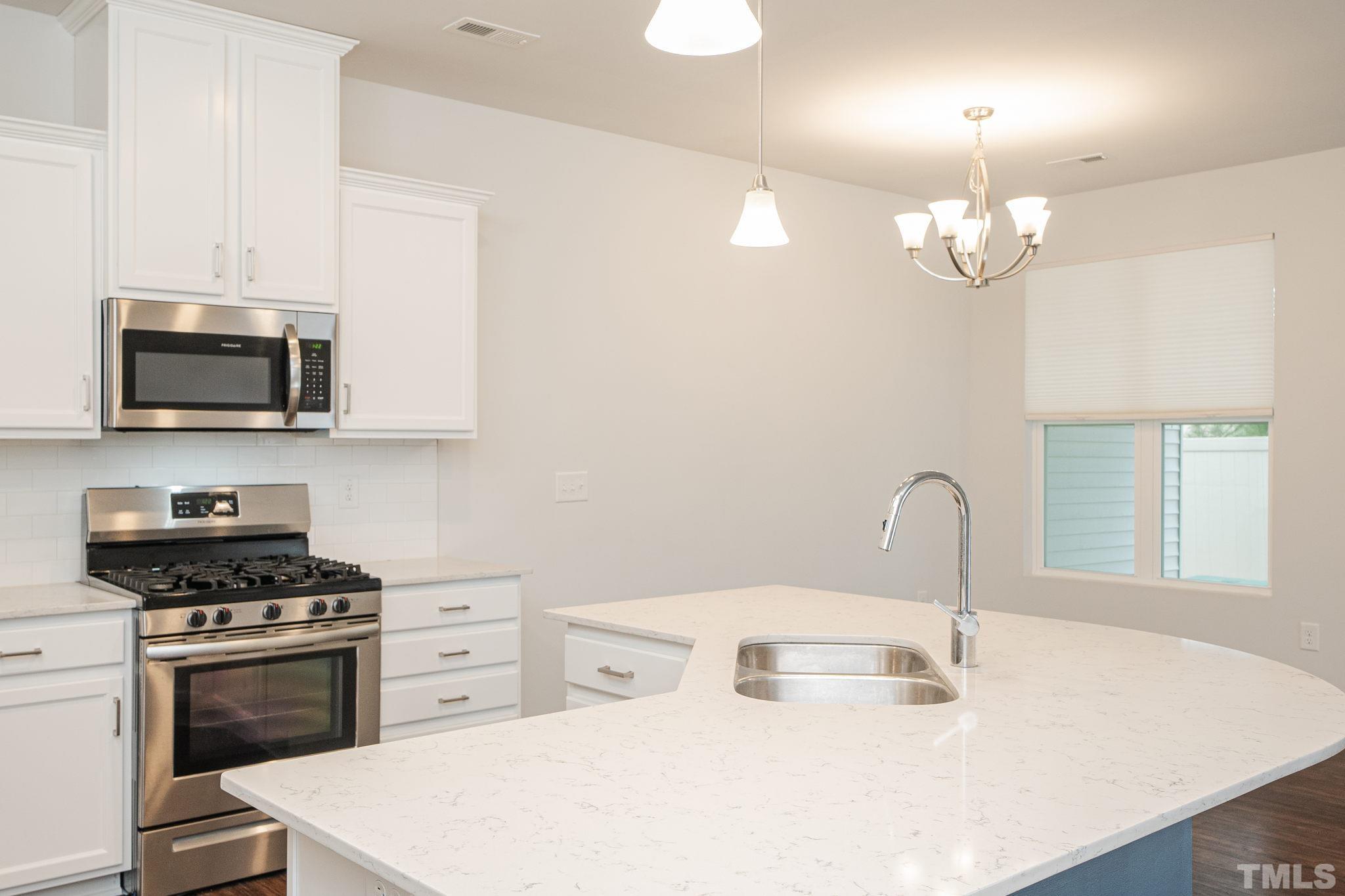 6075 Beale Loop Raleigh, NC 27616 - Photo 3 of 23 a kitchen with stainless steel appliances a sink a stove a microwave and a refrigerator