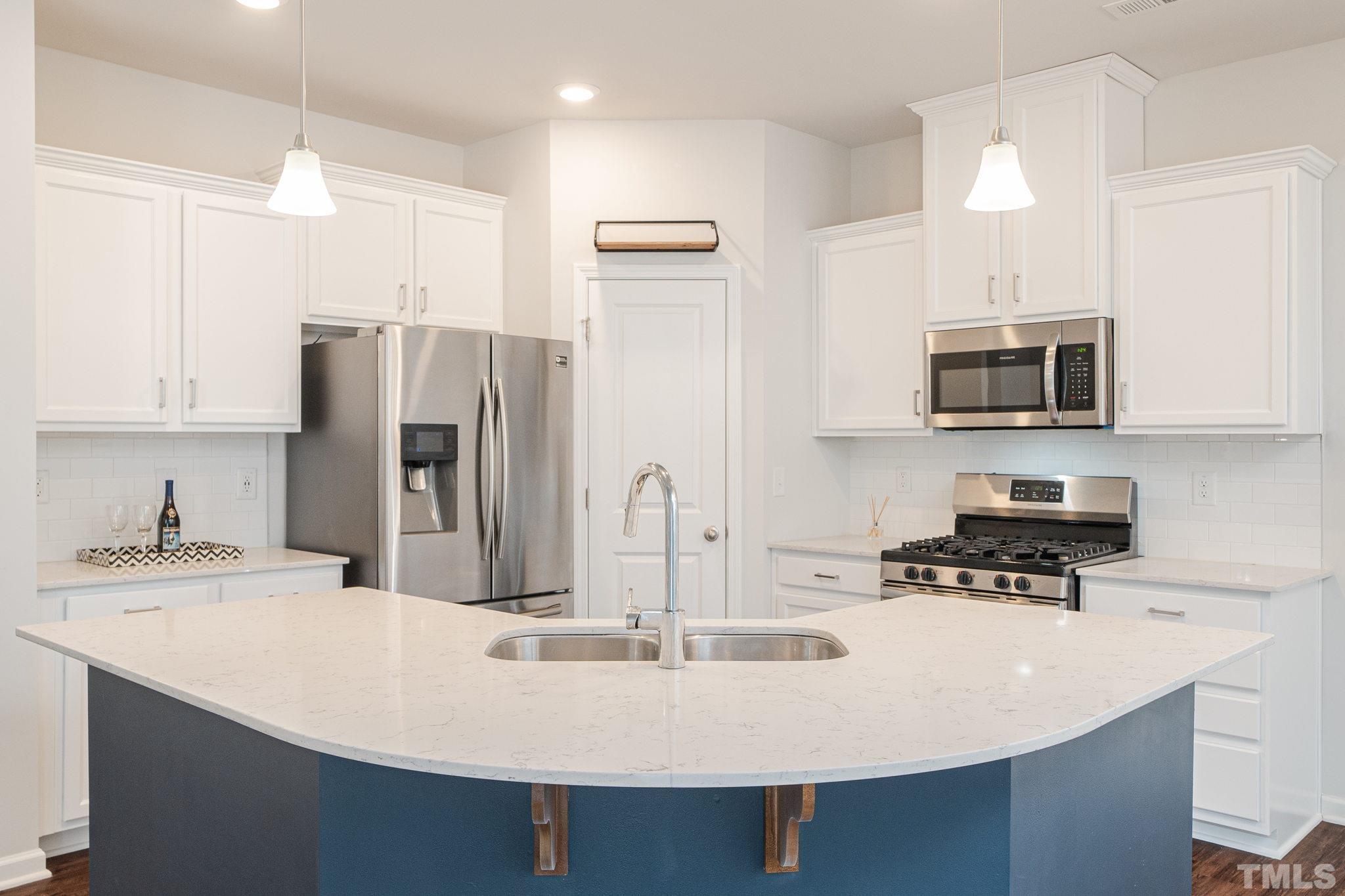 6075 Beale Loop Raleigh, NC 27616 - Photo 5 of 23 a kitchen with stainless steel appliances a sink a stove a microwave a refrigerator and cabinets