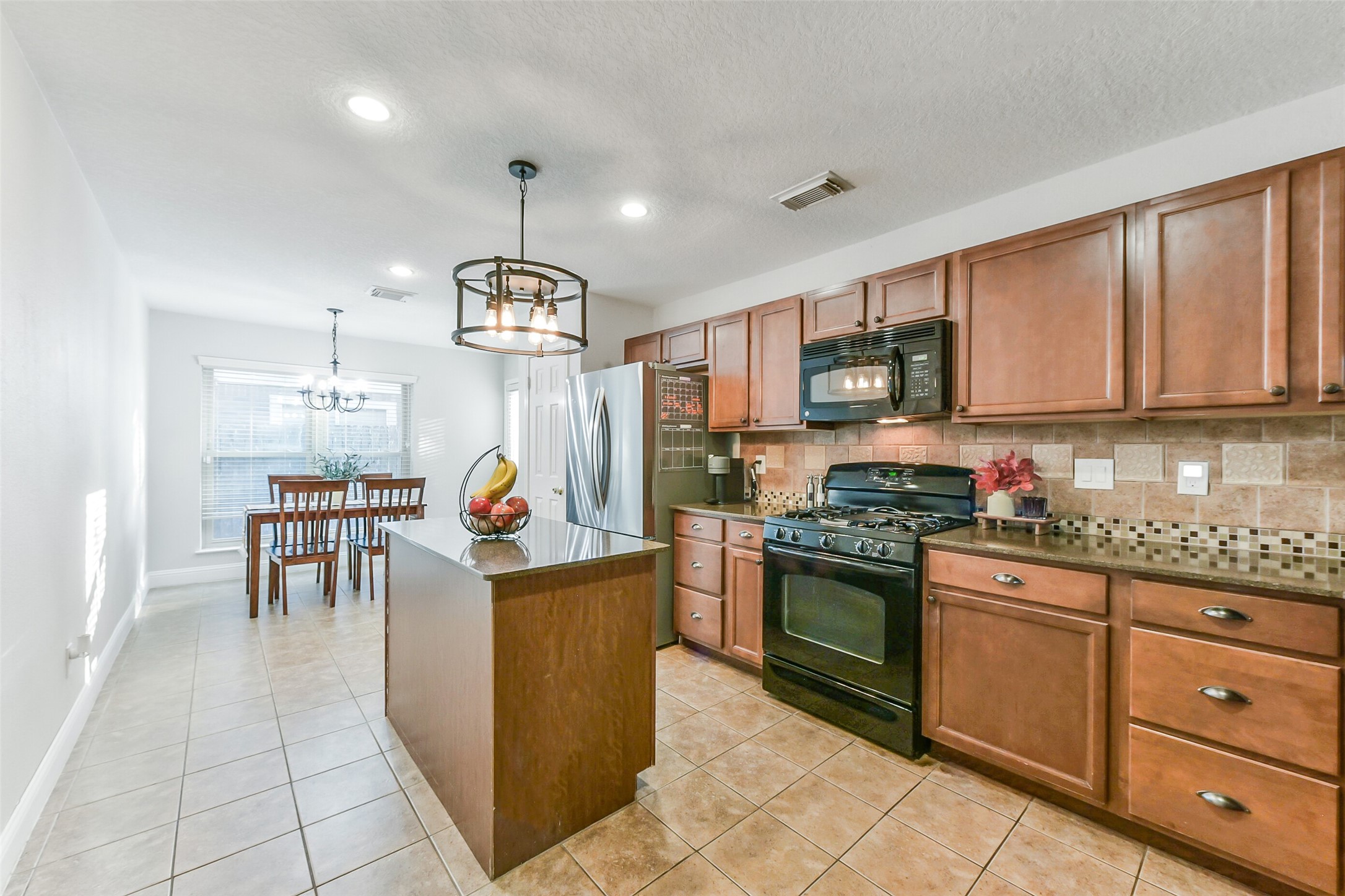 4010 Spring Branch Drive West Pearland, TX 77584 - Photo 10 of 35 a kitchen with granite countertop a stove a sink a dining table and chairs