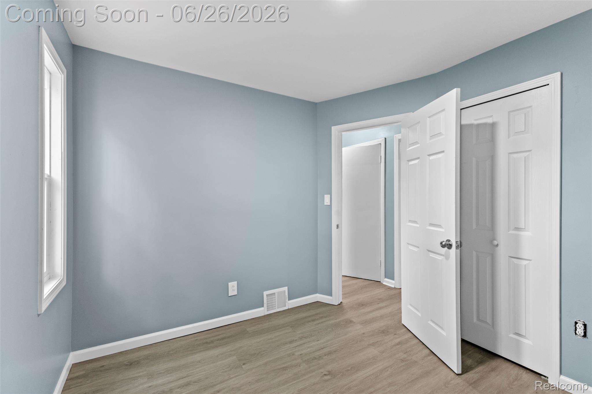 8310 Whitcomb Detroit, MI 48228 - Photo 19 of 26 Room featuring light blue walls, wood-finish flooring, white trim, and a white window frame