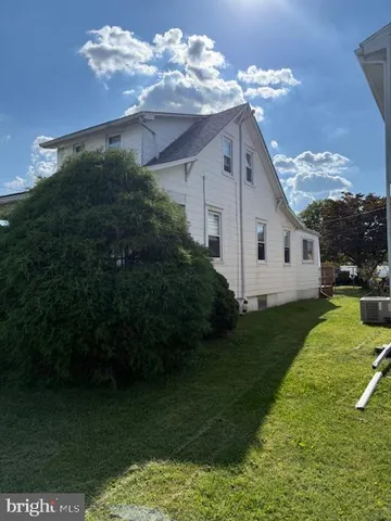 a view of a white house with a yard plants and large tree