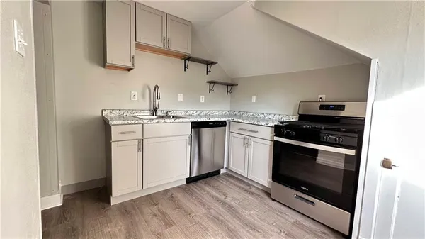 a kitchen with cabinets stainless steel appliances and wooden floor