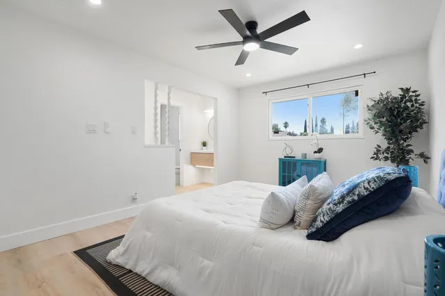 a bedroom with a bed painting on wall and a potted plant