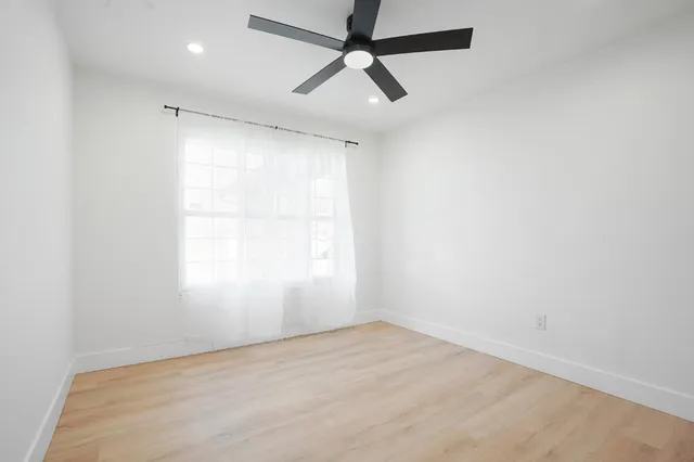 an empty room with a window and a fan