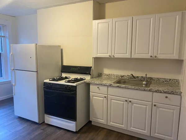 a kitchen with granite countertop white cabinets and a stove