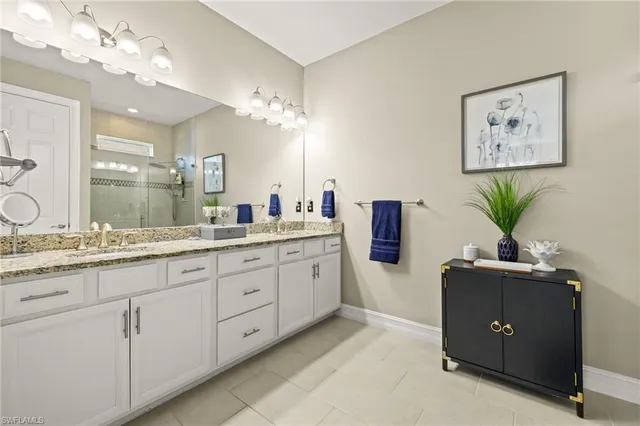 a spacious en suite bathroom with a granite countertop sink a mirror and a shower