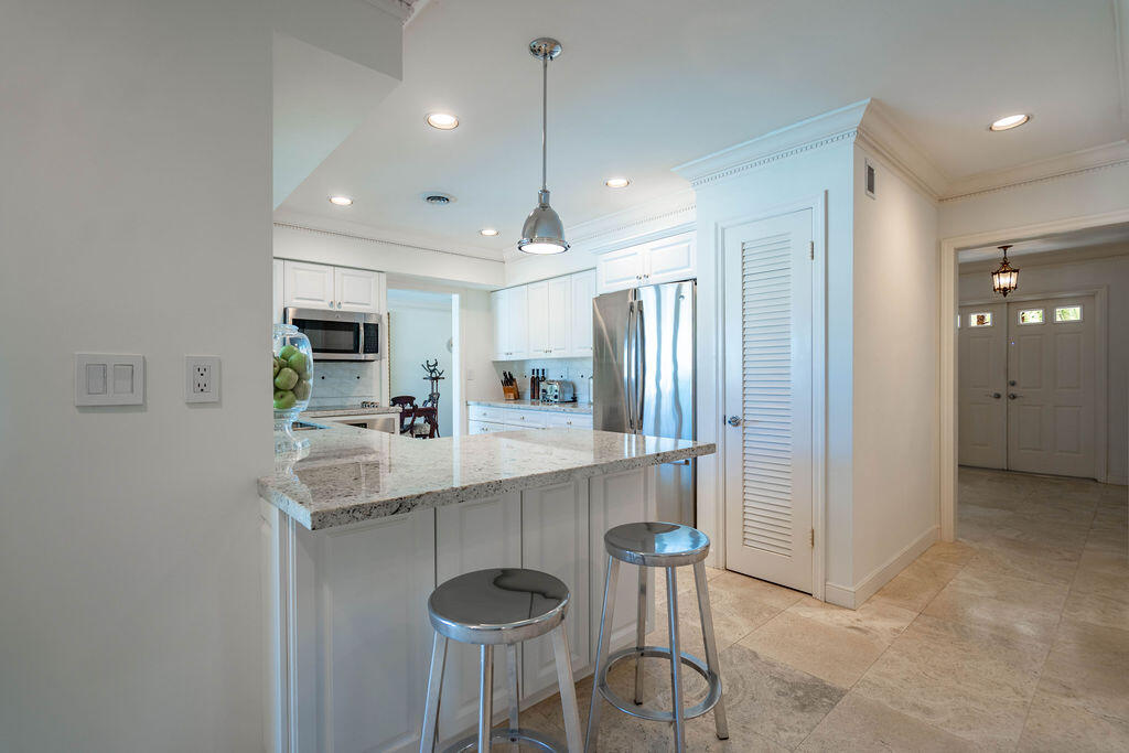 4450 Northeast 24th Terrace Lighthouse Point, FL 33064 - Photo 16 of 47 a kitchen with stainless steel appliances a dining table chairs refrigerator and sink