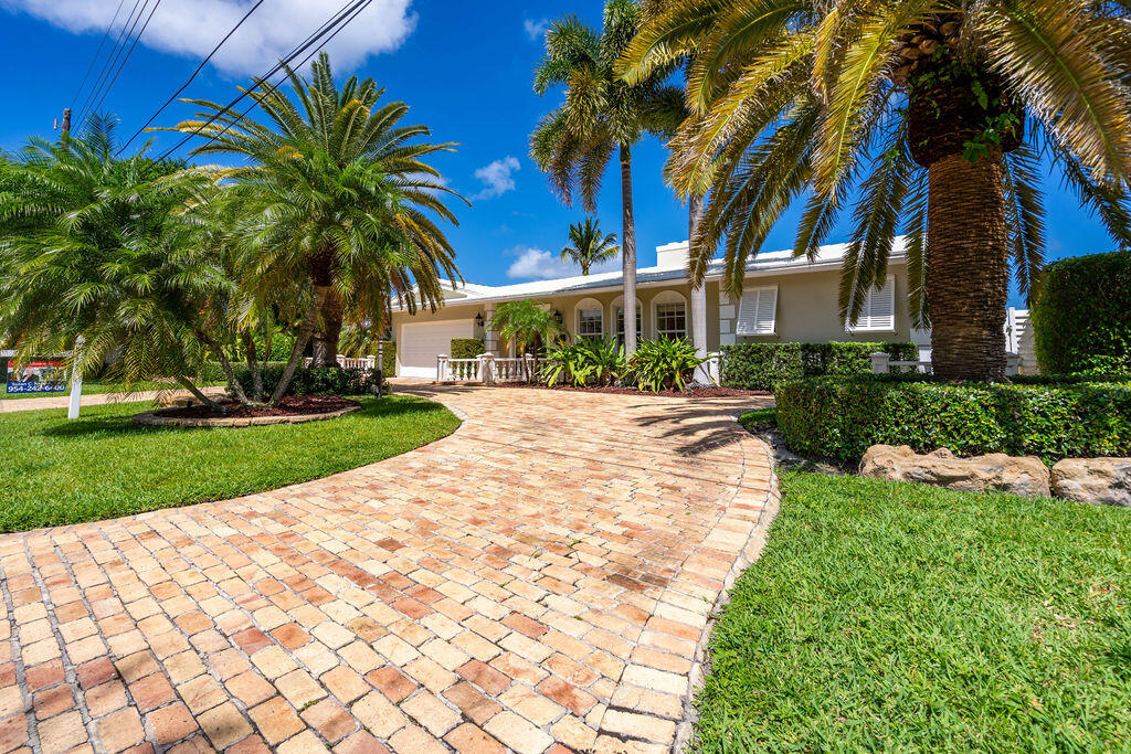 4450 Northeast 24th Terrace Lighthouse Point, FL 33064 - Photo 3 of 47 a front view of a house with a yard and palm trees