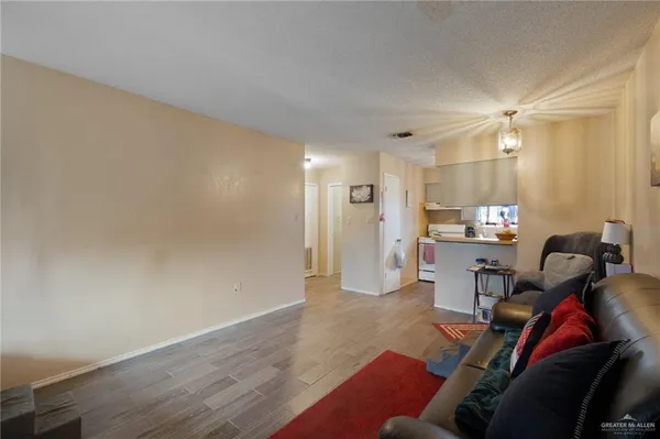 a living room with furniture a rug and kitchen view