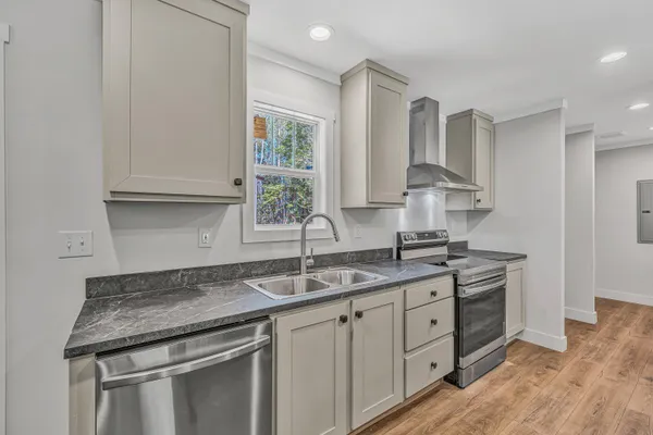 a kitchen with granite countertop a sink stainless steel appliances white cabinets and a window
