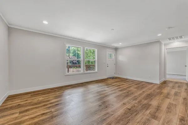 a view of an empty room with wooden floor and a window