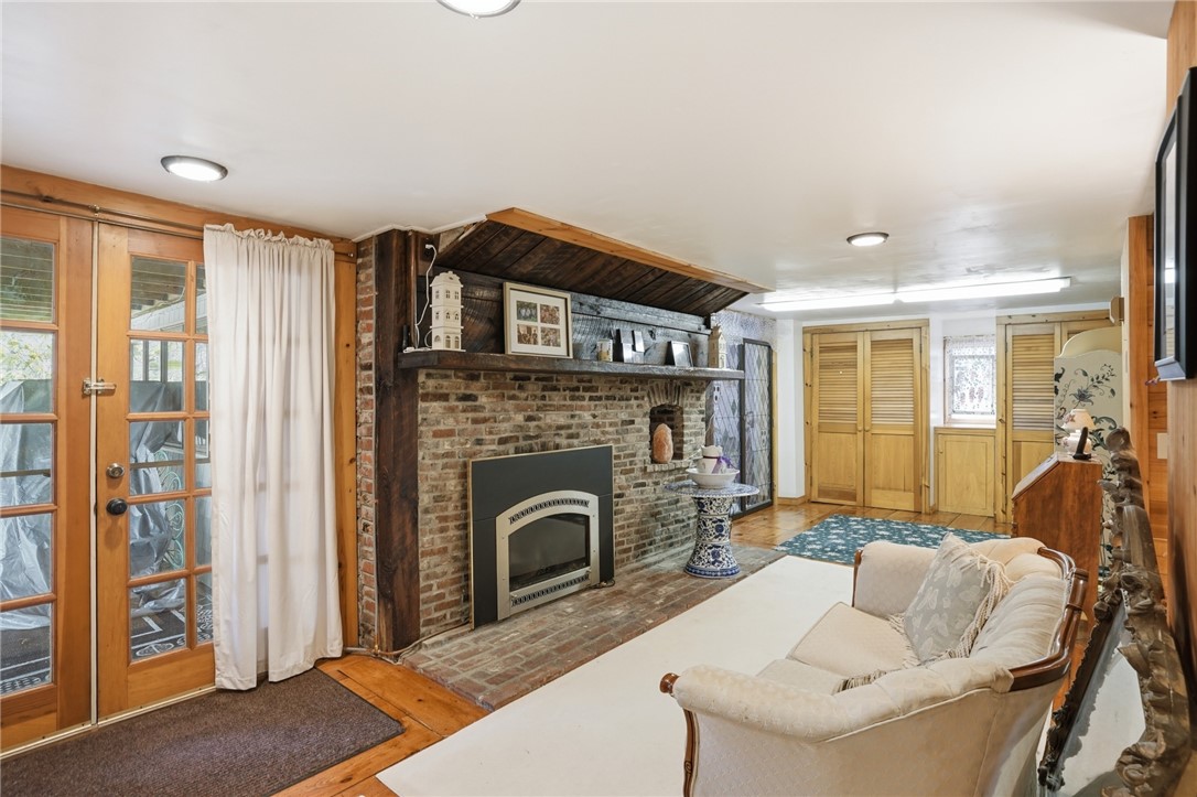 186 Arcadia Road Hopkinton, RI 02832 - Photo 22 of 27 This inviting lower level features a spacious family room complete with a walk-out to a lower deck, offering stunning river views. The room boasts a charming brick fireplace, creating a cozy ambiance, and provides ample additional storage solutions. Furthermore, there is a delightful bonus room with windows that additionally bring the outdoors in.