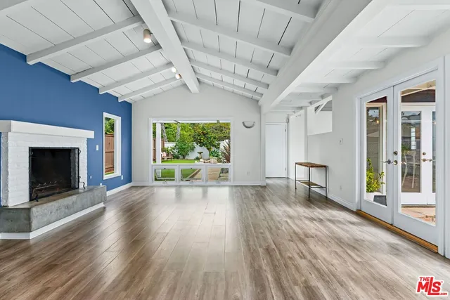 a view of an empty room with wooden floor and a fireplace
