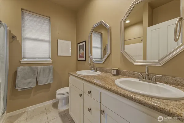 a bathroom with a granite countertop sink toilet and mirror