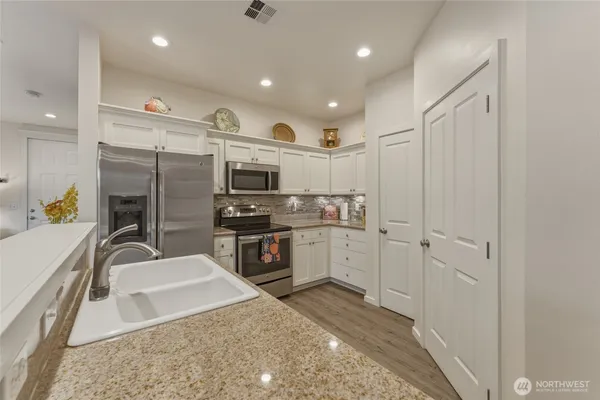a kitchen with stainless steel appliances granite countertop a sink refrigerator and microwave