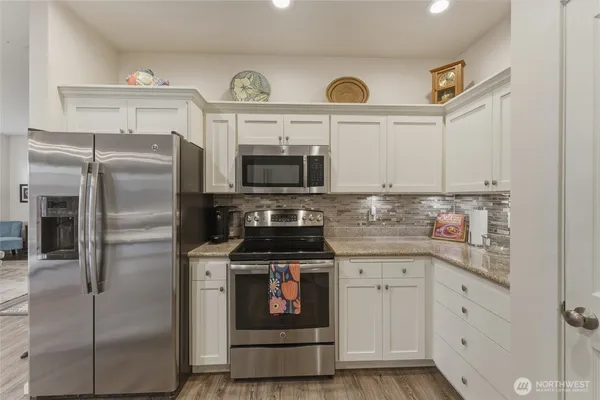 a kitchen with stainless steel appliances granite countertop a refrigerator a stove and a sink