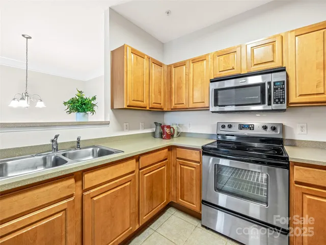 a kitchen with granite countertop a sink a stove top oven and cabinetry