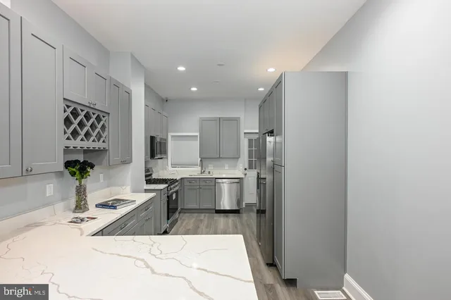 a large kitchen with stainless steel appliances a sink a refrigerator a counter top space and cabinets