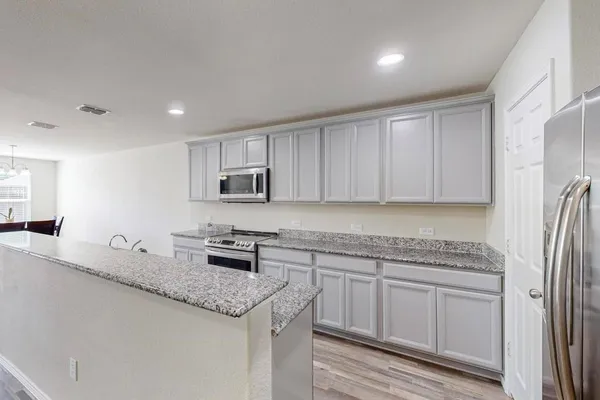 a kitchen with granite countertop cabinets stainless steel appliances a sink and wooden floor