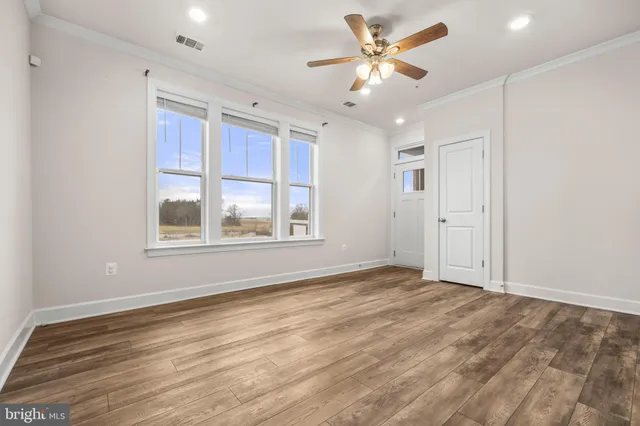 an empty room with wooden floor cabinet and windows