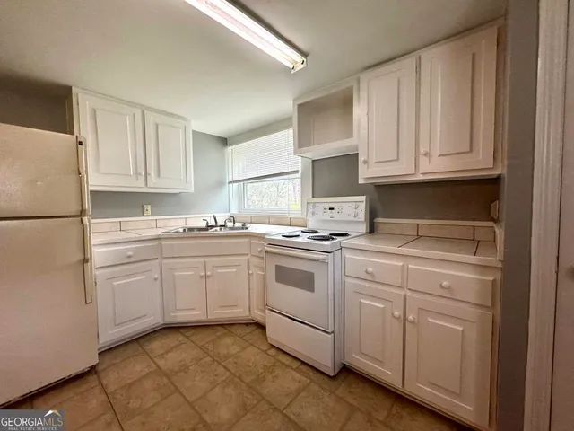 a kitchen with white cabinets and white appliances