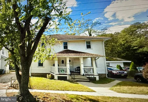 a view of a white house with large windows and a table and chairs under an umbrella