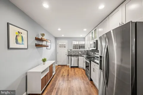 a kitchen with stainless steel appliances a refrigerator a stove a sink dishwasher and wooden cabinets with wooden floor