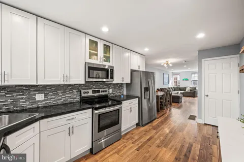 a kitchen with stainless steel appliances a stove top oven a refrigerator a sink and dishwasher with wooden floor